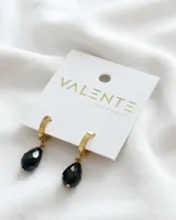 Aros dorados con charm en forma de gota negra, diseño elegante y minimalista.