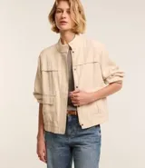 Campera bomber color beige confeccionada en viscosa, con cierre delantero, bolsillos con solapa y pespuntes contrastantes.
