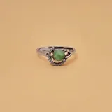 Anillo de plata 925 con una raíz de esmeralda redonda en el centro, rodeada de circonias. El diámetro de la piedra es de 6mm y el ancho de la alianza es de 2mm.
