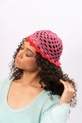 Gorro tipo bucket tejido a crochet, color rosa con borde rojo.