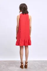 Vestido corto sin mangas, color celeste claro, con escote en V y un pequeño broche decorativo en la abertura frontal. Presenta un corte holgado tipo babydoll con bolsillos laterales y un ruedo con volado.