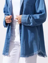 Camisa de jean celeste, marca Hester & Orchand, de corte oversize con cuello con solapa, escote en V y abertura central con botones. Delantera con bolsillos aplicados, mangas largas regulables con presilla y botón, y ruedo desflecado.