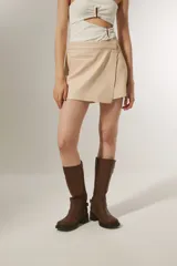Minifalda color beige con diseño cruzado y detalle de bolsillo lateral.