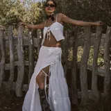 Pollera larga blanca de tiro alto, con volados en capas y abertura lateral ajustable con cordones.