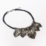 Collar corto con cordones negros y apliques metálicos plateados con forma de hojas.