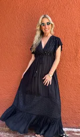 Vestido largo negro con escote en V, mangas cortas con volados, corte imperio con lazo ajustable y falda escalonada con detalles bordados.