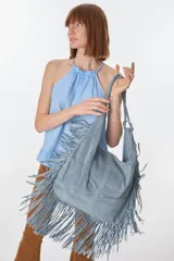 Bolso bandolera de gamuza color beige con flecos largos en la parte inferior.