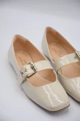 Chatitas tipo Mary Jane de charol negro con punta redondeada y tira sobre el empeine con hebilla metálica plateada.