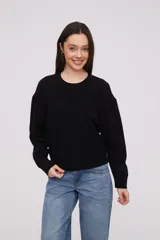 Sweater negro de manga larga y corte holgado, con textura suave.