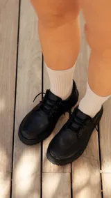 Zapato acordonado de cuero negro con suela track.