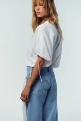 Camiseta blanca de algodón con cuello redondo, corte recto y mangas cortas ajustables con lazadas.