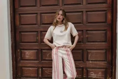 Remera color crudo de corte recto, con cuello redondo y mangas cortas con ribete rojo. Estampado pequeño de un sol en el pecho.