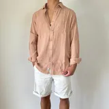 Camisa de lino color beige, de corte oversize, con cuello clásico y mangas largas con puños abotonados.