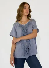 Camisa de lino y algodón color rosa claro, con cuello en V, mangas cortas y volados frontales.