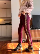 Pantalón bordó de corte recto, con bolsillos laterales y una franja dorada con estampado animal print en los laterales.