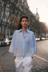 Camisa celeste de popelina con cuello solapa y manga ancha por debajo del codo. Bajo acabado con bordados perforados. Cierre frontal con botones.