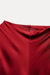 Vestido midi rojo de satén con cuello alto y sisas amplias. Cierre en la espalda con abertura y botones.