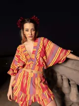 Conjunto de short y top con estampado a rayas rojas, amarillas y violetas. El top es corto con escote en V y mangas cortas anchas. El short es de tiro alto con volados en el ruedo.