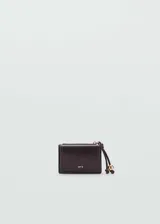 Monedero pequeño color beige con efecto piel y detalle de abalorios. Tiene cierre de solapa con botón magnético, bolsillo interior y bolsillo lateral con cierre de cremallera.