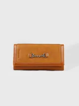 Billetera de cuero color camel con solapa y cierre de broche magnético. Presenta un detalle metálico plateado en el frente y el logo de la marca grabado en el lateral.