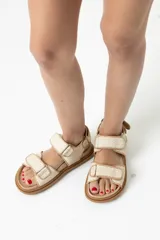 Sandalias planas color beige con tiras de rafia y ajuste con velcro.