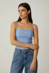 Musculosa celeste de bretel fino, ajustada al cuerpo y con estampado de flor en el pecho.