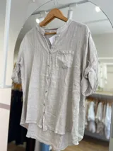 Camisa celeste de lino, con cuello mao, manga 3/4 con botón para sujetar, cierre frontal con botones y bolsillo de parche en el pecho.