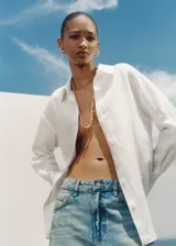 Camisa blanca de lino, de corte oversize, manga larga con puños abotonados, cuello camisero y cierre frontal con botones.