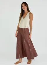 Pollera larga negra de corte amplio, con costuras verticales que simulan pliegues y terminaciones deshilachadas. Se combina con una musculosa negra de escote redondeado.