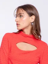 Top de manga larga color rojo con cut out en el escote y cuello alto, confeccionado en tela texturada.