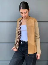 Campera marrón con cuerpo de cuero y mangas de lana color beige. Interior con estampado animal print. Corte clásico con cuello redondo y cierre frontal con botones a presión.