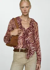 Blusa de manga larga con estampado abstracto en tonos borgoña y beige. Presenta cuello pico con volantes y cierre de lazo en la parte delantera.