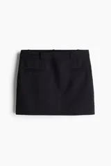 Minifalda negra de sarga con corte sastrero, bolsillos insertados en el frente, bajo recto y forro interno.