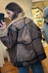 Campera gamulán marrón con cuello y puños de piel sintética color beige. Cierre frontal con cremallera y bolsillos laterales.