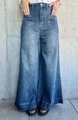 Pantalón de jean azul de corte pata de elefante, con bolsillos frontales tipo parche.