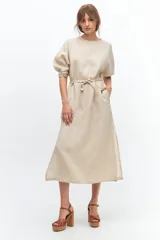 Vestido midi color coral confeccionado en lino. Tiene corte recto, mangas abullonadas con detalle de tablas en el puño, tajos laterales y lazo en la cintura.