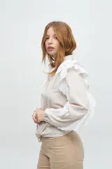 Camisa de algodón con volados en las mangas y sisa, color beige, con un botón dorado en la parte frontal.