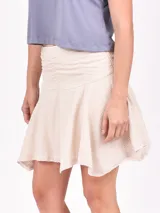 Minifalda de tejido texturizado color crudo, con cintura elastizada y ruedo desflecado.