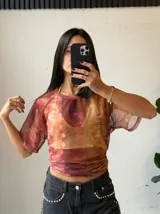 Remera de microtul con estampado abstracto en tonos marrones, naranjas y rojos.