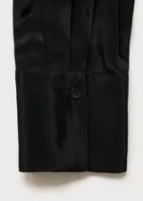 Blusa azul con lazo al cuello, de tejido fluido y satinado, con cierre oculto de botones y mangas largas abotonadas.