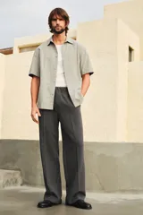 Camisa de manga corta color gris claro, de tejido texturizado con cuello inglés, tapeta lisa, canesú en la espalda y bajo recto con aberturas laterales.