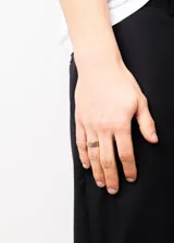 Anillo tipo alianza de acero quirúrgico hipoalergénico con acabado satinado color plateado y bordes dorados.