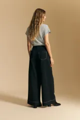 Pantalón ancho de tiro alto, color negro, con costuras contrastantes en blanco que definen los bolsillos y los bordes.