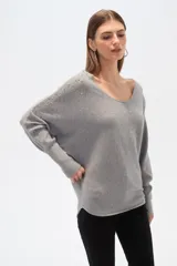 Sweater negro de tejido acanalado, corte holgado tipo murciélago con mangas largas ajustadas en puños. Escote bote adornado con apliques de pedrería plateada que se extienden por los hombros y mangas.