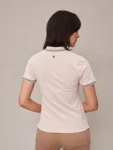 Remera polo blanca de piqué con cuello sin botones y mangas cortas con ribete a rayas rojas y azules. Corte clásico.