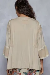 Blusa blanca de corte amplio, escote en V y mangas 3/4 con detalles de broderie.