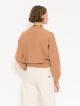 Sweater color camel de tejido cerrado, con cuello redondo y mangas largas.
