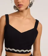 Blusa cropped negra de lino y algodón, con escote corazón, breteles anchos y detalle de bordado ondulado en el ruedo.