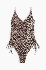 Traje de baño enterizo con estampado animal print de leopardo, escote en V, tirantes finos ajustables, copas con relleno extraíble, espalda baja y cordones laterales para fruncir.