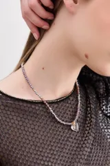 Collar corto de cuentas plateadas, lilas y marrones con dije transparente en forma de corazón.